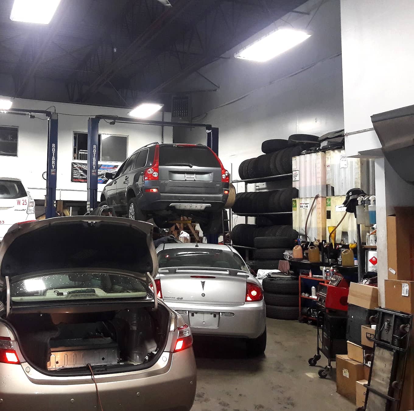 Inside the Abbotsford Tune-Up Centre workshop: an SUV raised on a Rotary lift, cars in the bays and racks of tires